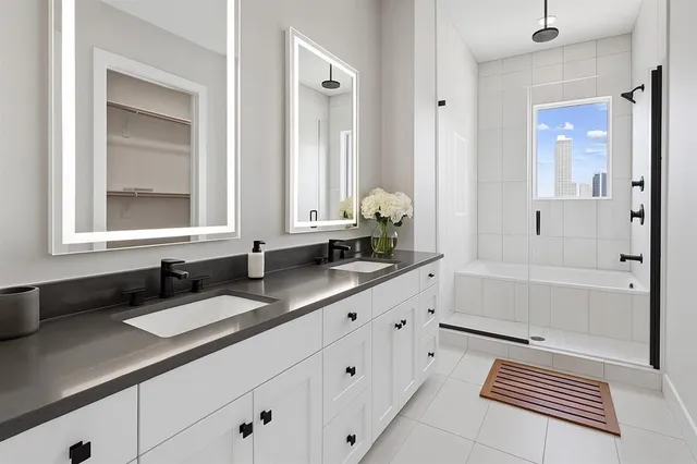 a bathroom with double vanity sink a mirror and a shower