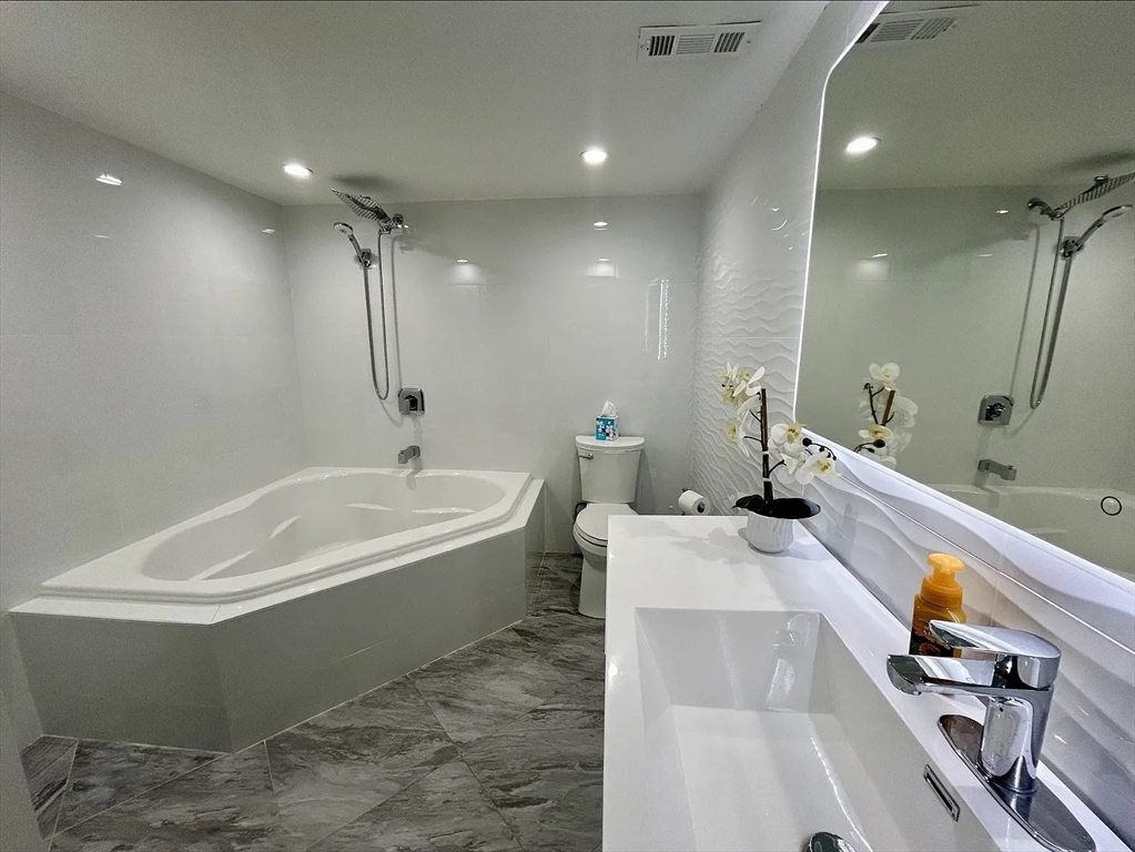 a bathroom with a tub a sink and a large mirror