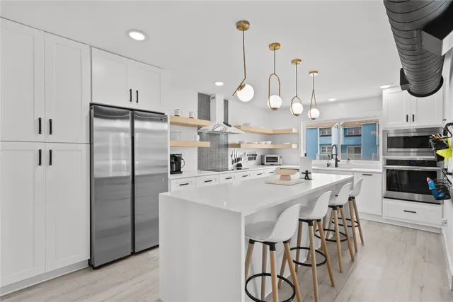a kitchen with stainless steel appliances a table chairs stove and refrigerator