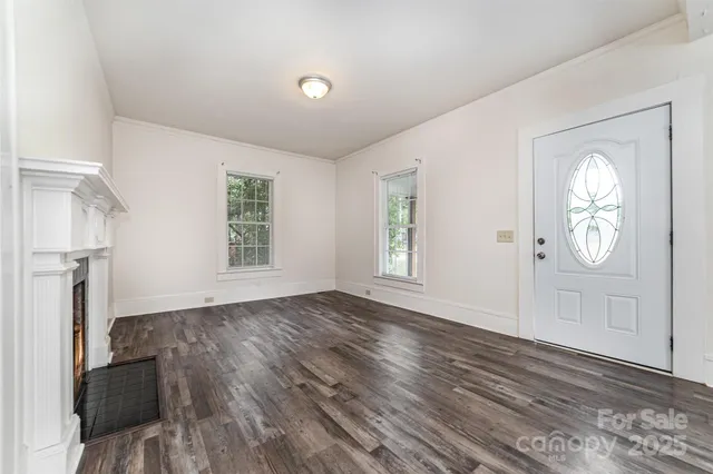 an empty room with wooden floor cabinet and windows
