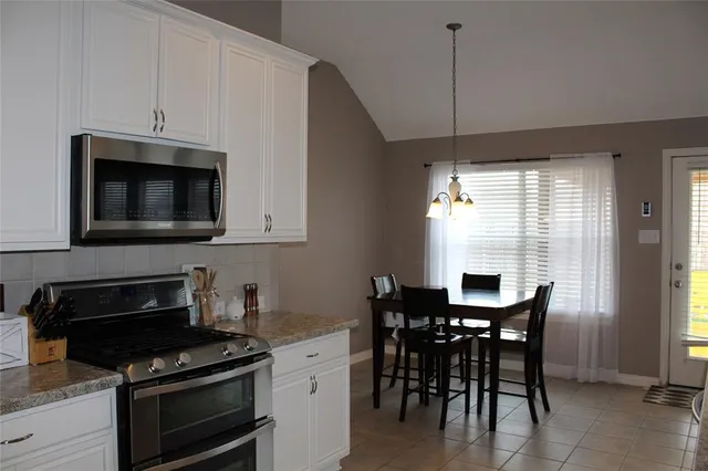 a kitchen with stainless steel appliances granite countertop a stove a sink a microwave a dining table and chairs with wooden floor