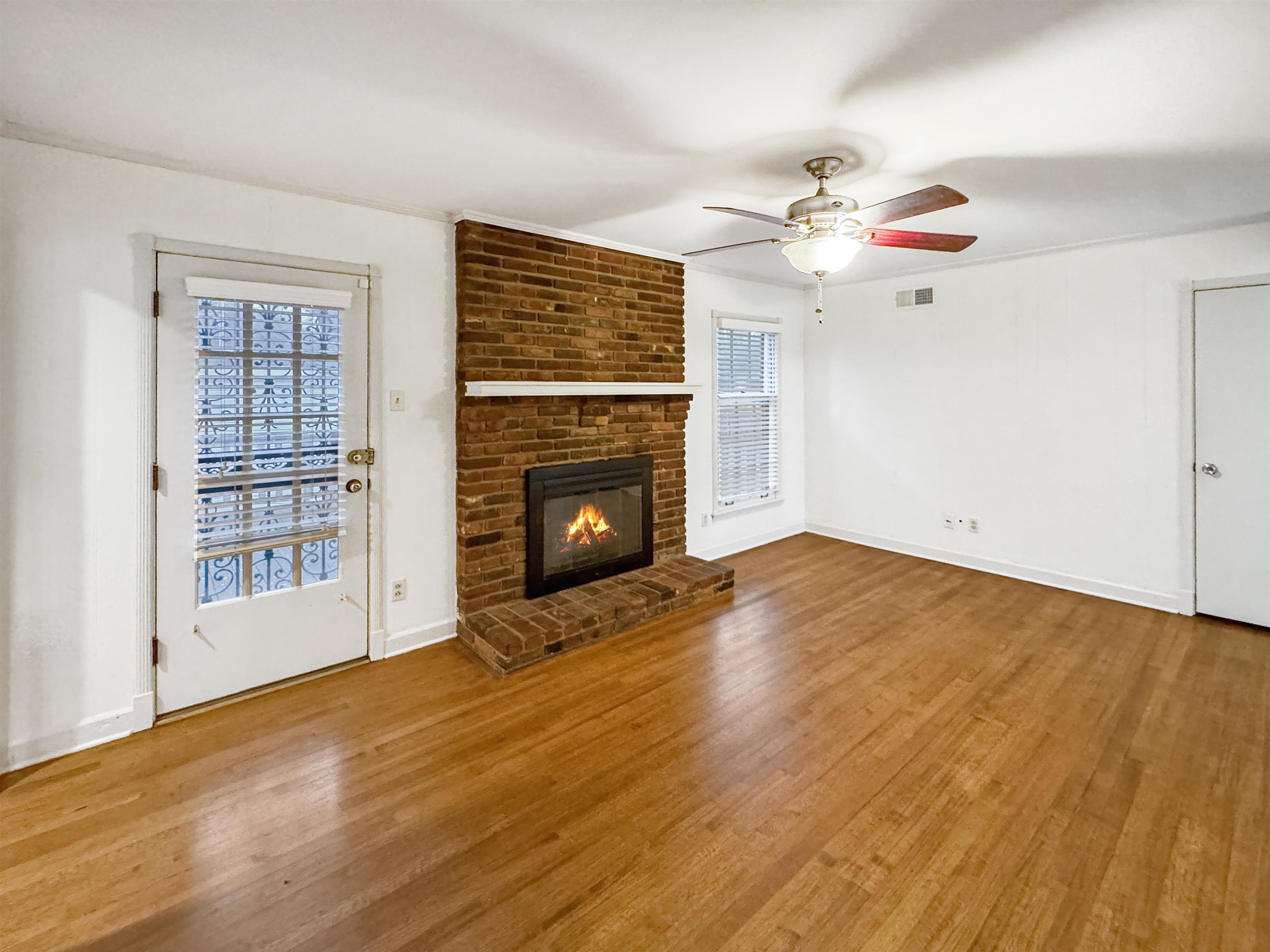 407 Meadvale Road Memphis, TN 38120 - Photo 16 of 37 an empty room with windows fireplace and wooden floor