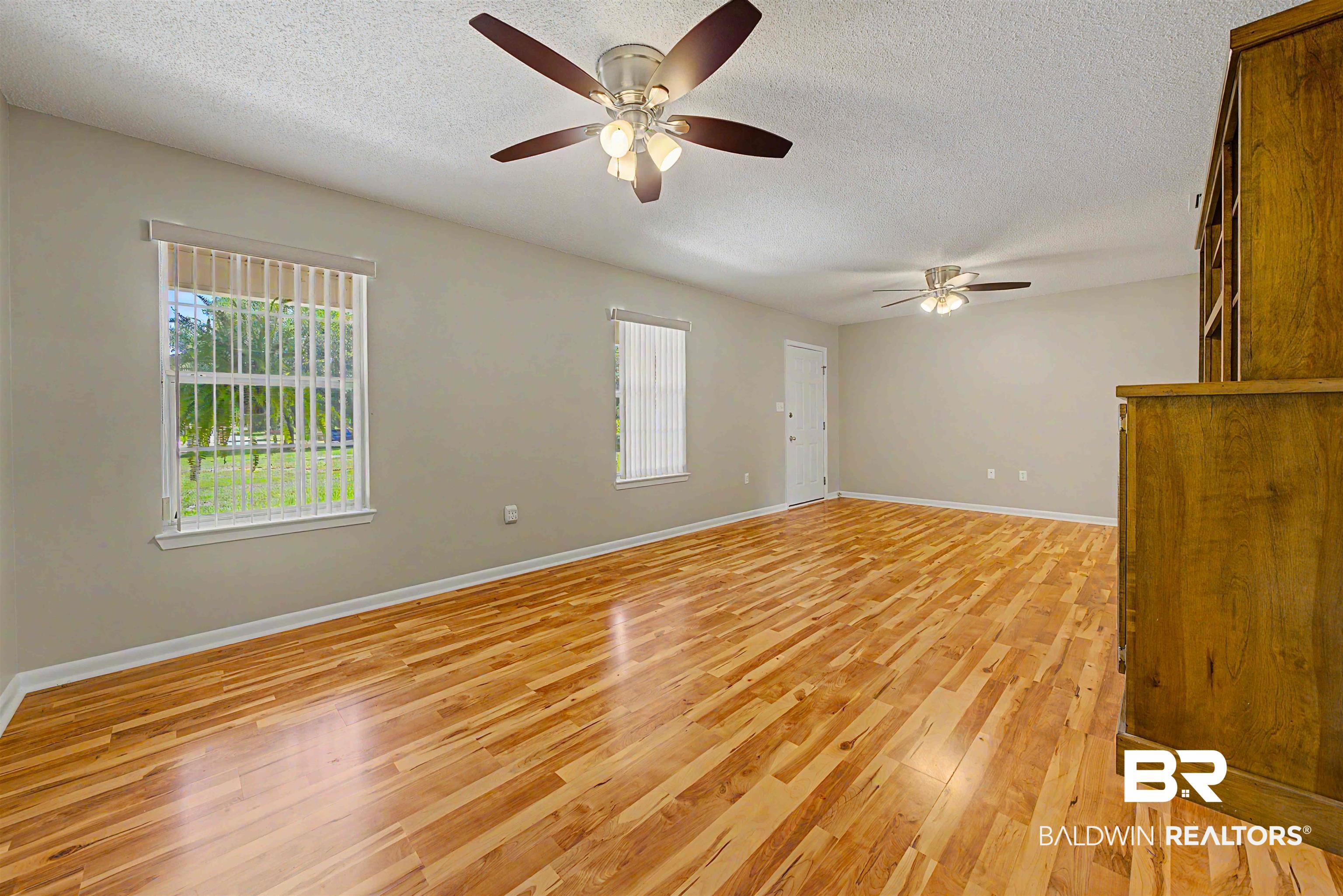 22963 Highway 98 Foley, AL 36535 - Photo 31 of 52 Spacious interior with wood-finish flooring, light grey walls, and two ceiling fans with integrated lighting