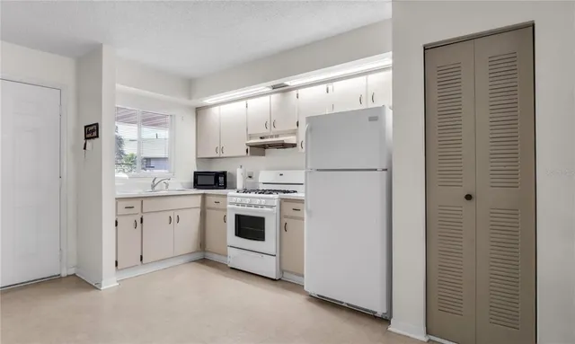 a kitchen with white cabinets and white appliances