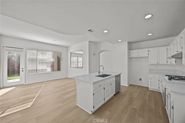 a large white kitchen with stainless steel appliances granite countertop a lot of counter space and wooden floor
