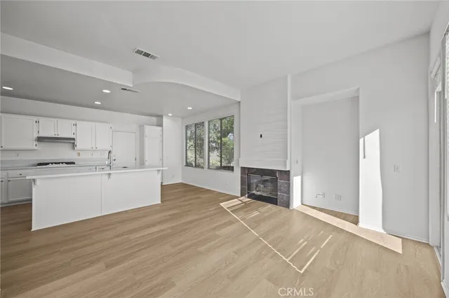 a large white kitchen with a stove a sink dishwasher and a refrigerator with wooden floor