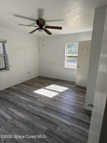 an empty room with wooden floor closet and windows