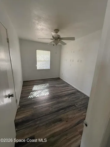 an empty room with wooden floor and fan