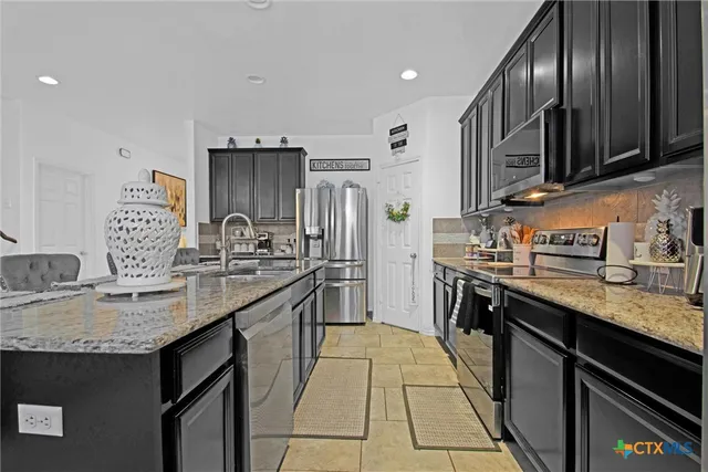 a kitchen with stainless steel appliances granite countertop a sink stove and refrigerator