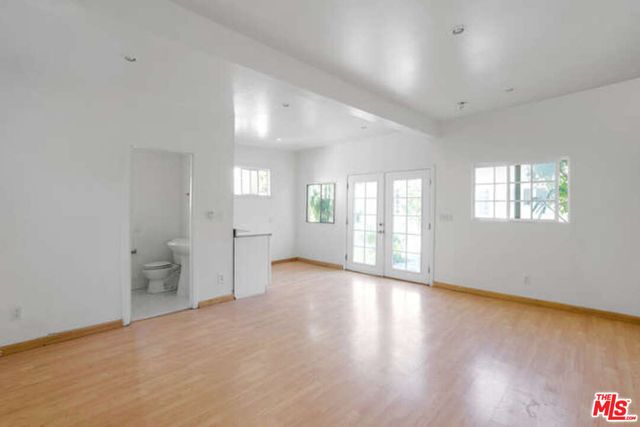 a view of a kitchen with wooden floor and white cabinets