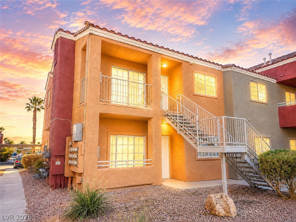 A terracotta-hued exterior building with an outdoor staircase under a vivid sunset sky.