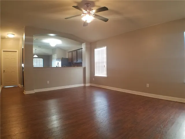 a view of an empty room with window and wooden floor