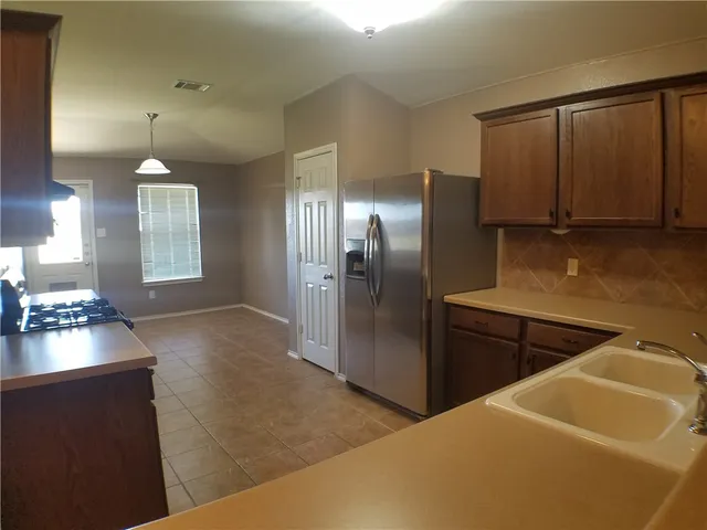 a kitchen with stainless steel appliances granite countertop a refrigerator a sink and a stove