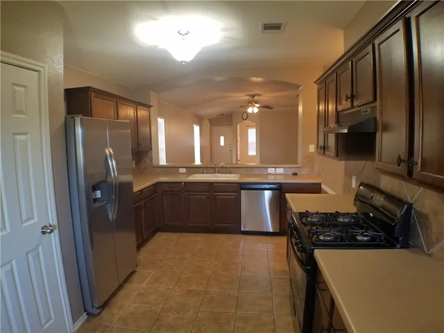 a kitchen with stainless steel appliances granite countertop a refrigerator and a stove