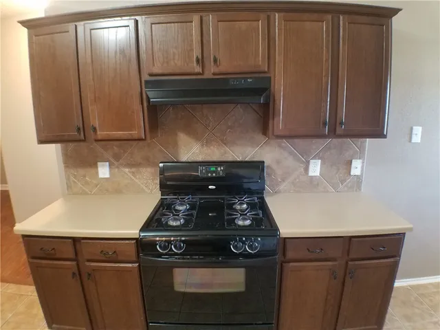 a kitchen with wooden cabinets and a stove top oven