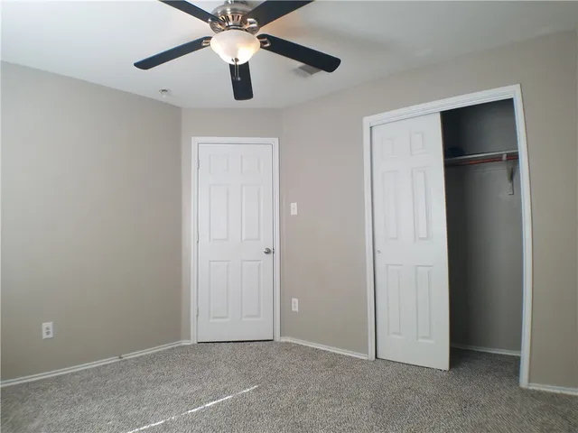 an empty room with closet and a chandelier fan