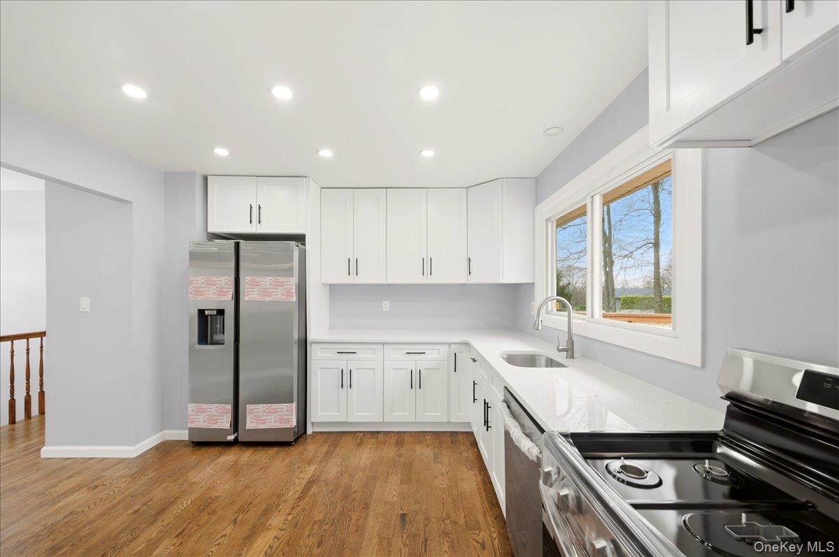7 Gene Road Middletown, NY 10941 - Photo 12 of 43 Kitchen featuring stainless steel appliances, white cabinets, recessed lighting, light wood-type flooring, and light stone counters