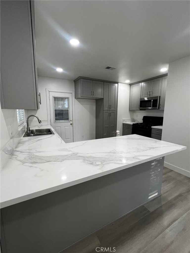 7442 Potomac Street Riverside, CA 92504 - Photo 4 of 8 a large kitchen with kitchen island a sink stainless steel appliances and cabinets