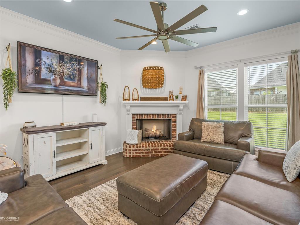 690 Lessie Drive Stonewall, LA 71078 - Photo 8 of 29 Living area featuring wood-finish flooring and a corner fireplace with a brick surround and white mantel