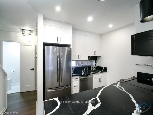 a kitchen with granite countertop a refrigerator stove and sink