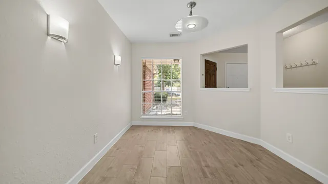 an empty room with wooden floor and windows