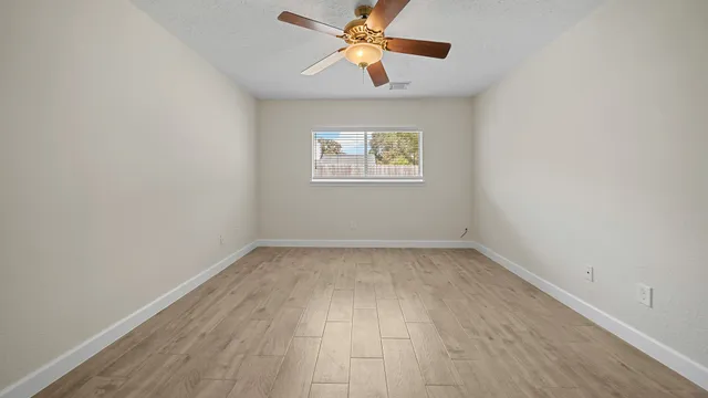 an empty room with a window and a fan