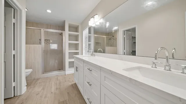 a spacious bathroom with a double vanity sink a large mirror and shower