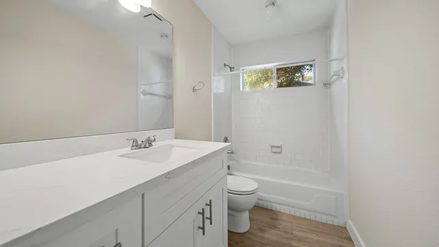 a bathroom with a granite countertop sink toilet a mirror and shower