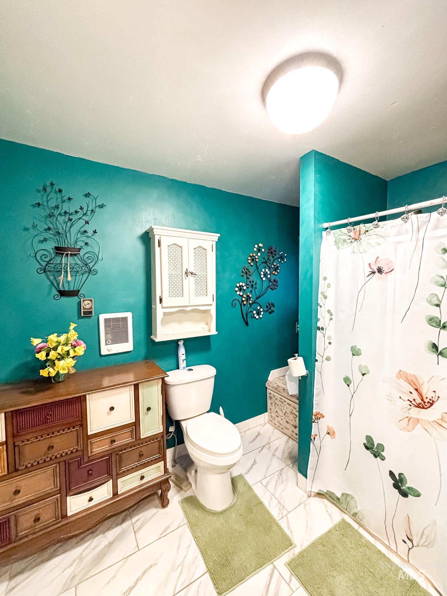 1995 Glenwood Road Kamiah, ID 83536 - Photo 14 of 38 Bathroom featuring a white toilet, floor-mounted vanity with varied drawer fronts, white wall-mounted storage cabinet, and large-format tile flooring