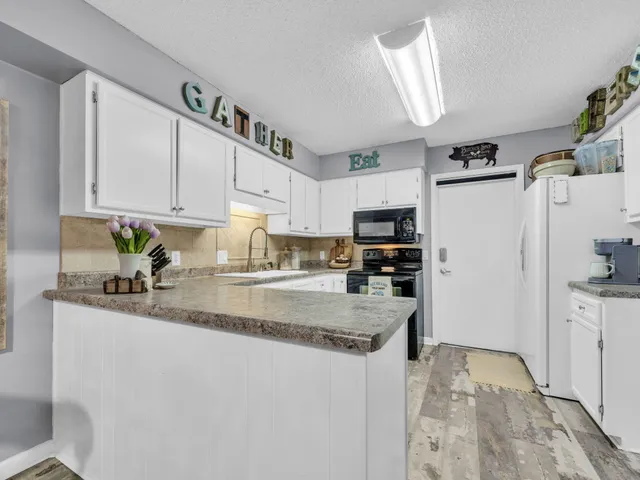 a kitchen with stainless steel appliances granite countertop a refrigerator a stove a sink dishwasher and white cabinets with wooden floor