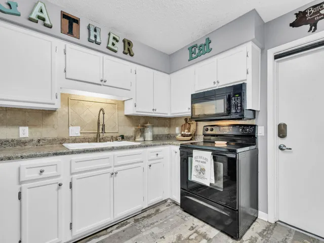 a kitchen with granite countertop white cabinets stainless steel appliances and a sink