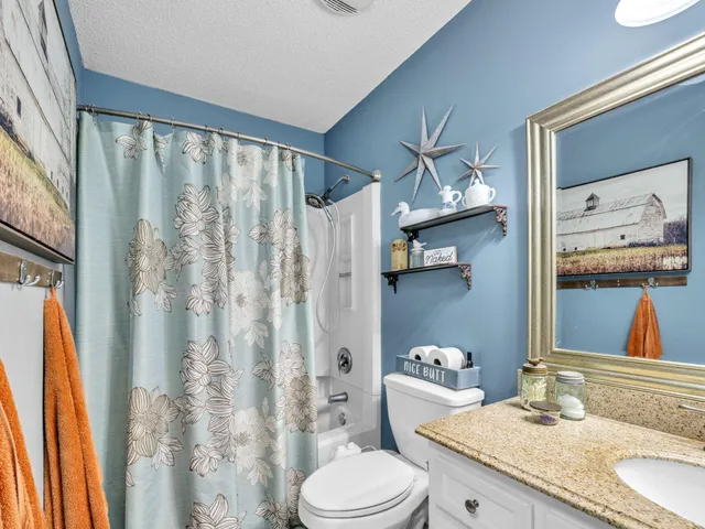 a bathroom with a granite countertop bathtub sink vanity mirror and toilet