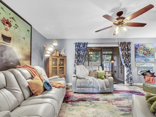 a living room with furniture ceiling fan and a large window