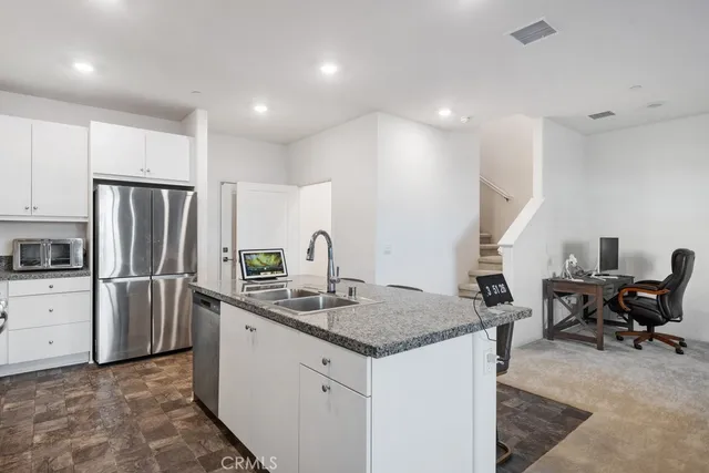 a kitchen with stainless steel appliances granite countertop a sink refrigerator and chairs