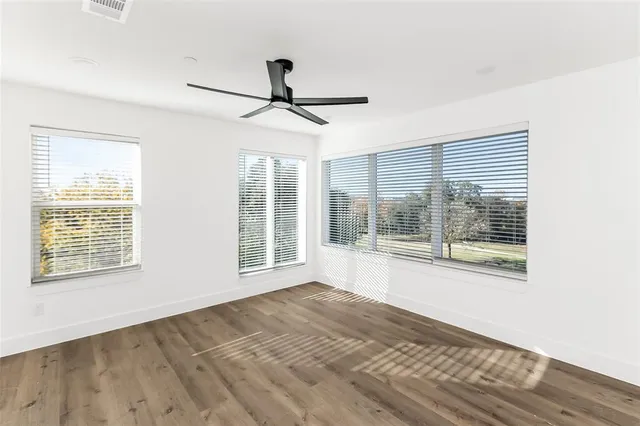 a view of an empty room with a window and wooden floor