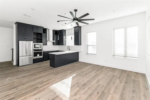 a view of kitchen with stainless steel appliances wooden floor and a window