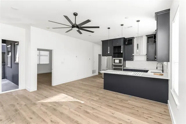 a large kitchen with stainless steel appliances kitchen island granite countertop a refrigerator and a sink