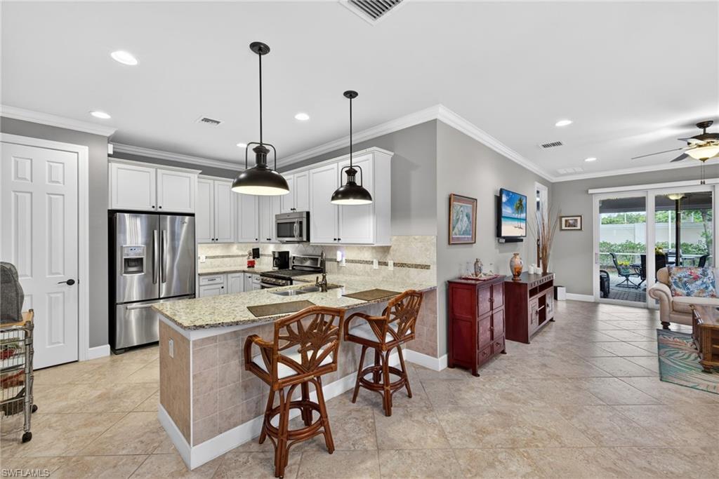 20105 Torch Key Way Estero, FL 33928 - Photo 10 of 29 a kitchen with stainless steel appliances kitchen island granite countertop a table chairs and a refrigerator
