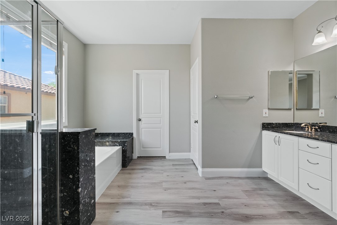 312 Pocono Ranch Avenue North Las Vegas, NV 89031 - Photo 21 of 34 Bathroom featuring baseboards, wood finished floors, a garden tub, and vanity