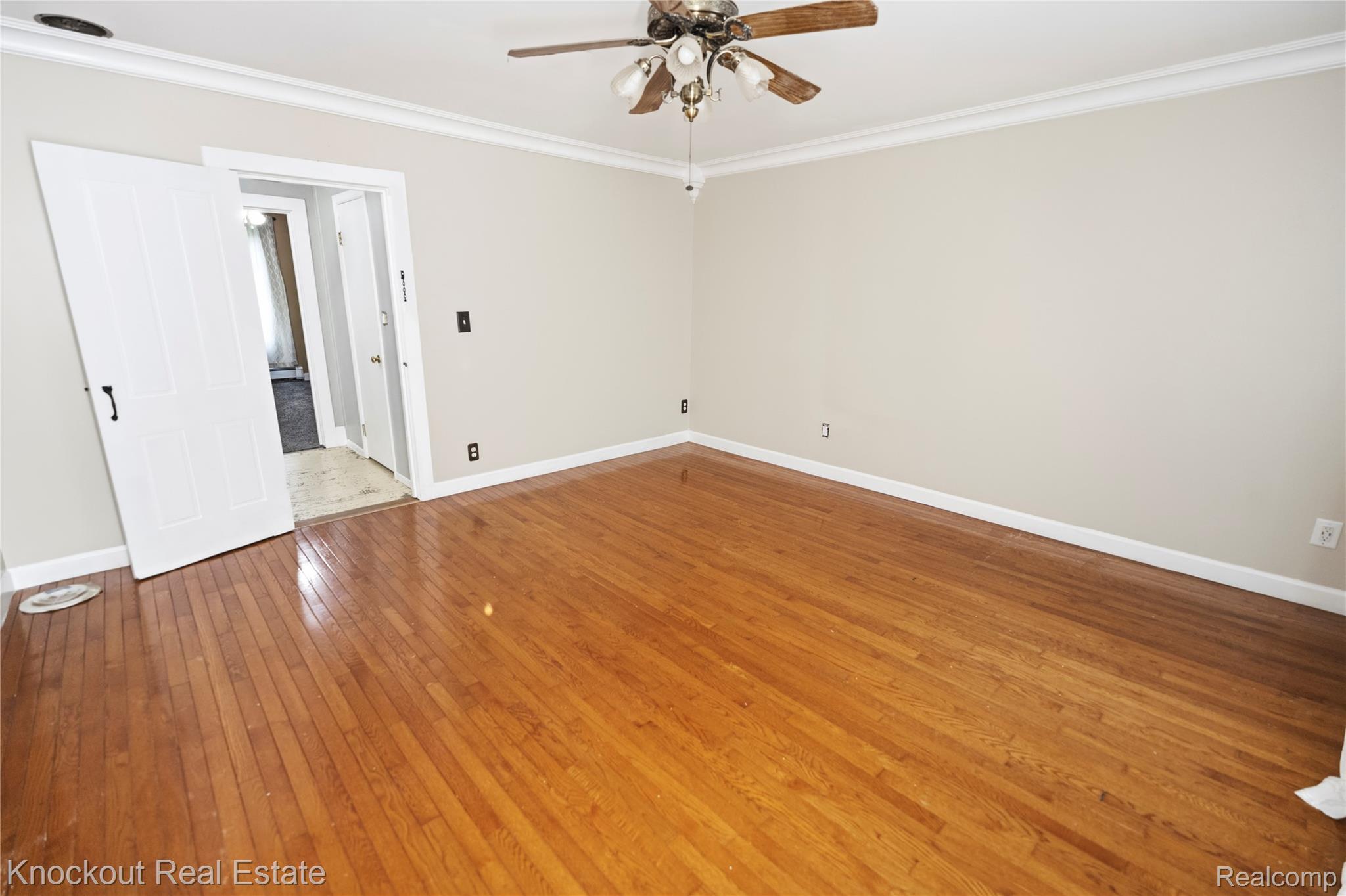 5750 Maple Road Frankenmuth, MI 48734 - Photo 27 of 60 Hardwood flooring, painted walls, crown molding, and a ceiling fan with light fixture