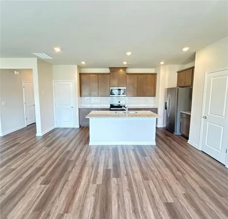 a large white kitchen with wooden floors and stainless steel appliances