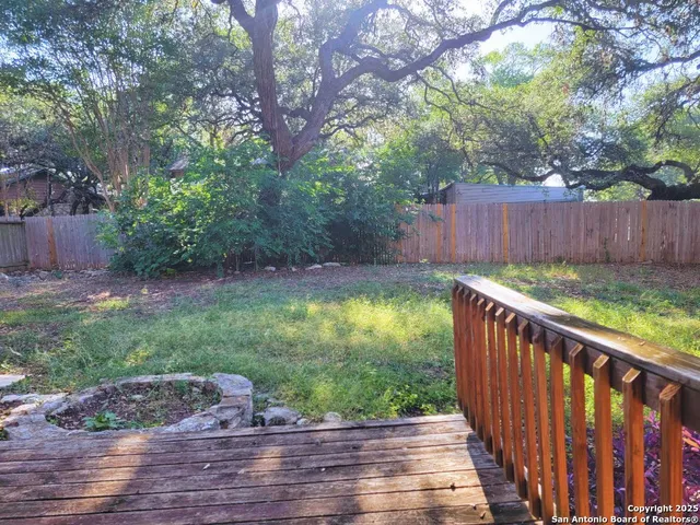 a view of a backyard with a large tree and wooden fence