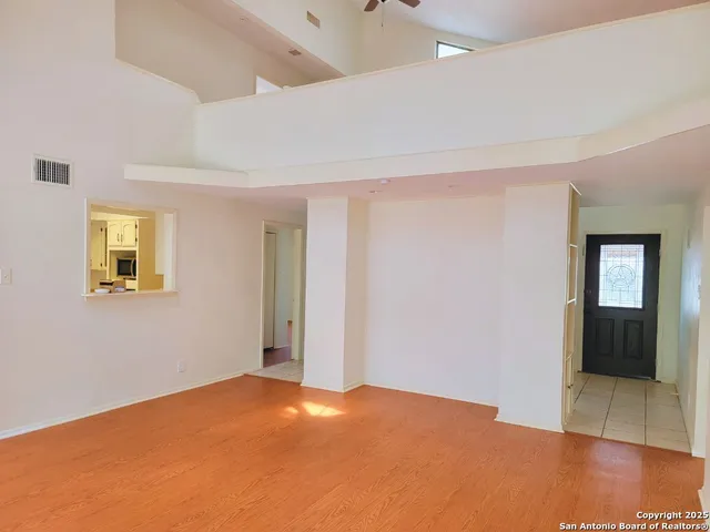 a view of an empty room with window and wooden floor