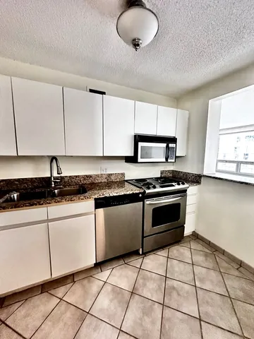 a kitchen with granite countertop a stove a sink and a refrigerator