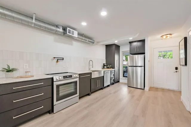 a kitchen with granite countertop a refrigerator and a stove top oven
