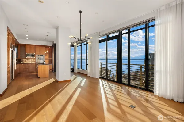 a view of an empty room with kitchen and a window