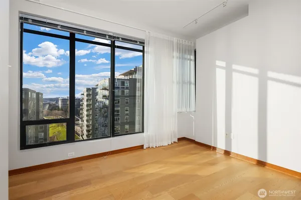 a view of an empty room with window and wooden floor