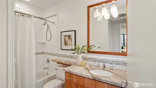 a bathroom with a granite countertop sink toilet a mirror a vanity and shower