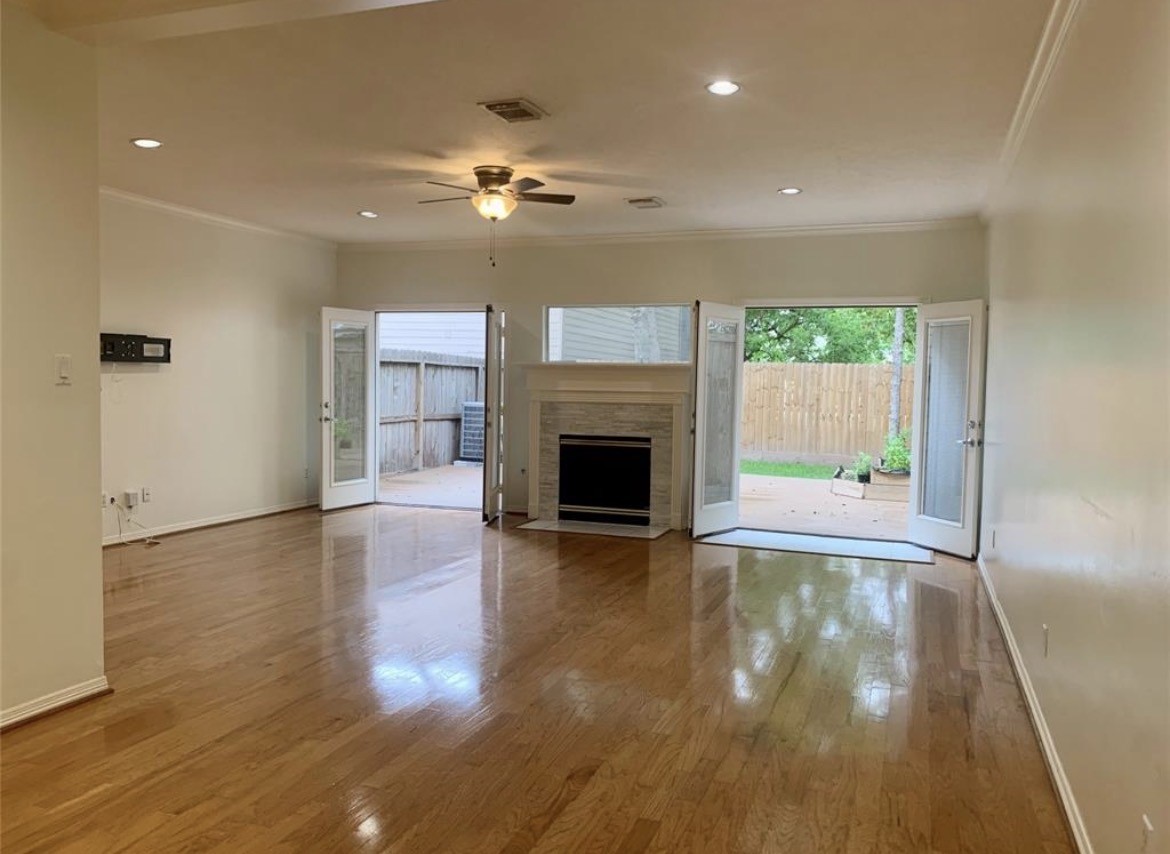 4916 Maxie Street Houston, TX 77007 - Photo 1 of 8 a view of a livingroom with wooden floor a ceiling fan and a kitchen