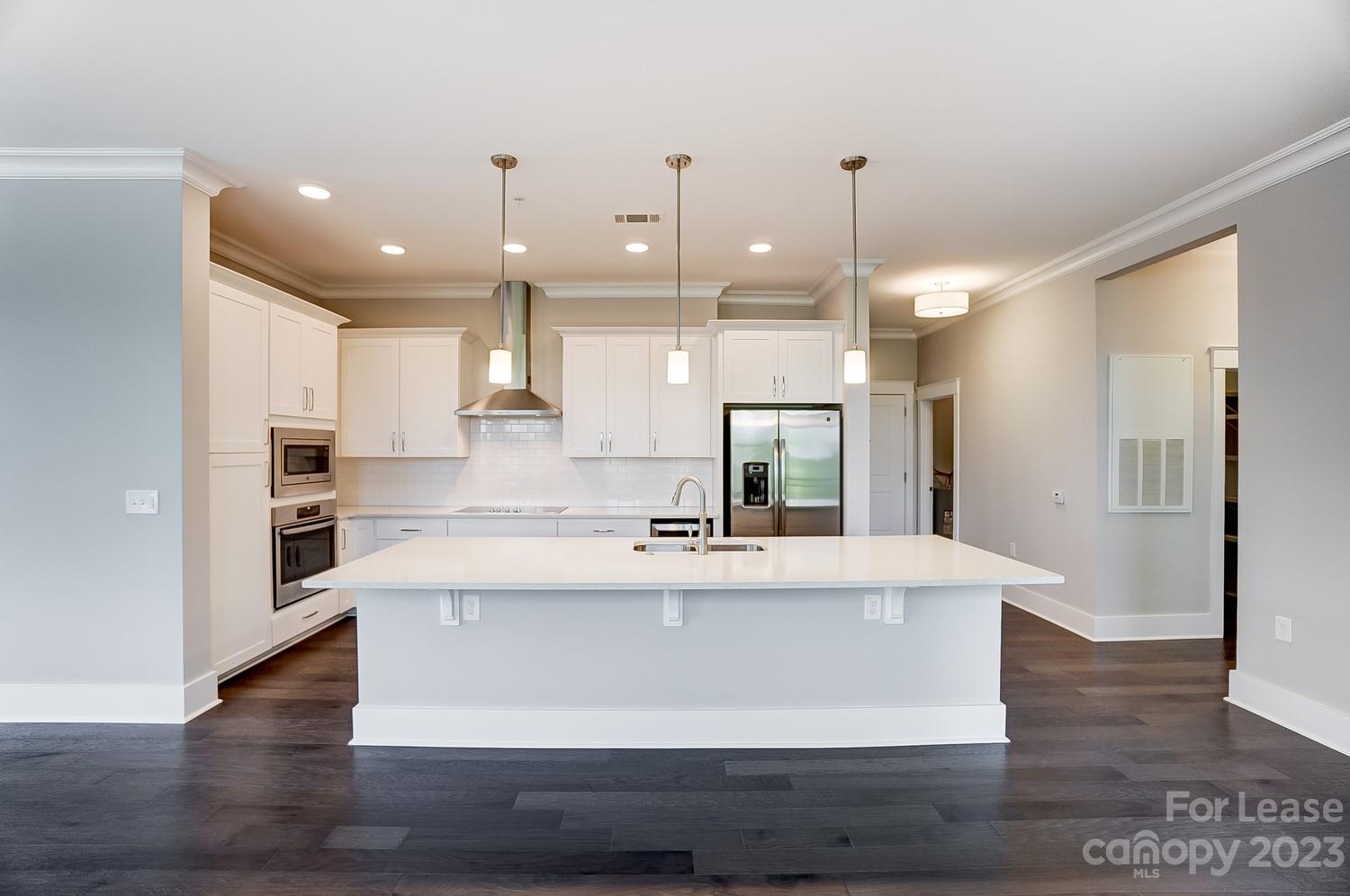 830 Providence Road, Unit 104 Charlotte, NC 28207 - Photo 5 of 21 a large white kitchen with a large island oven a sink stainless steel appliances and cabinets